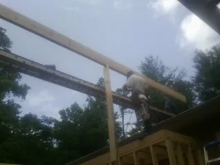 Carpenter setting a ridge beam over a new addition frame — Ice Dam Removal by Roofing Brothers in Ridgway