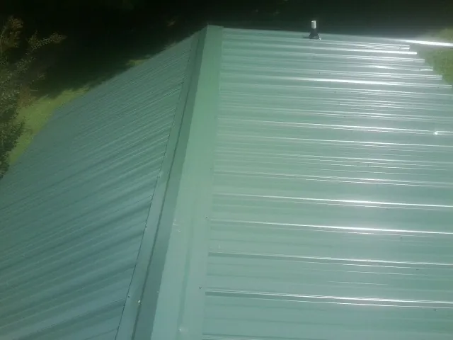 New green metal panels meeting at the ridge of a roof — Flat Roof Repair work by our crew in Ridgway