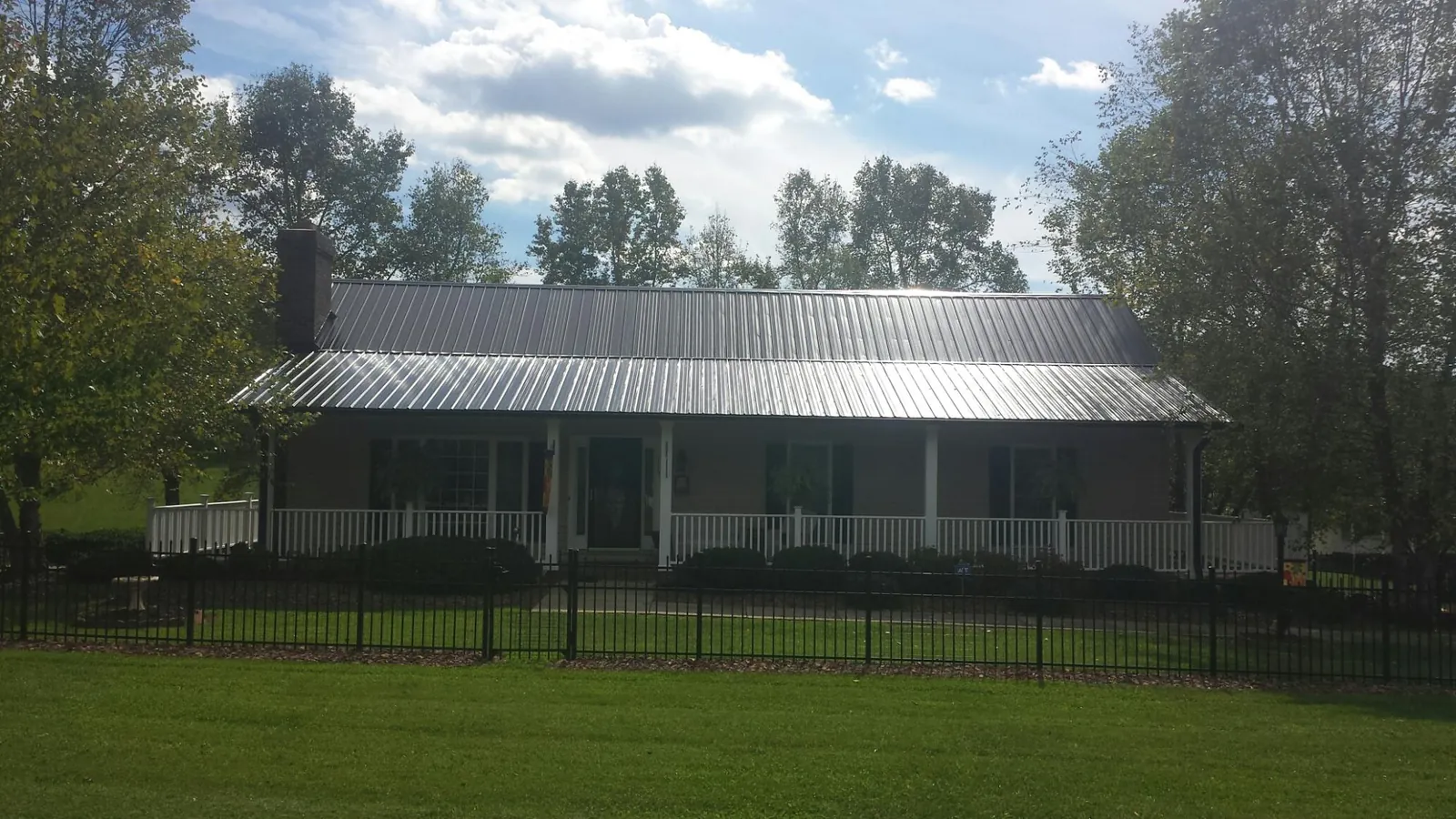 Gray metal roof on a brick ranch with a full width front porch — Gutter Guard Installation work by our crew in Ridgway