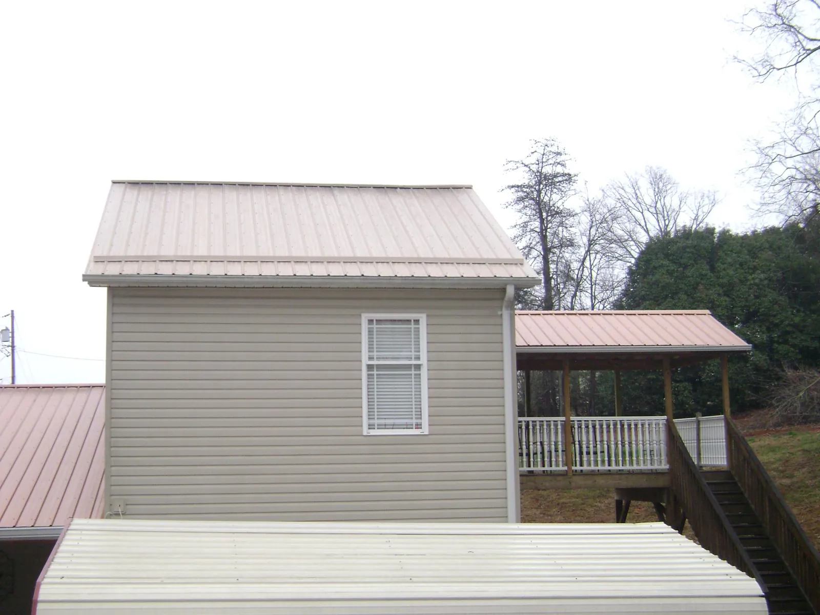 Tan metal roofs on a two story addition and attached porch, from a Roof Replacement job in Ridgway