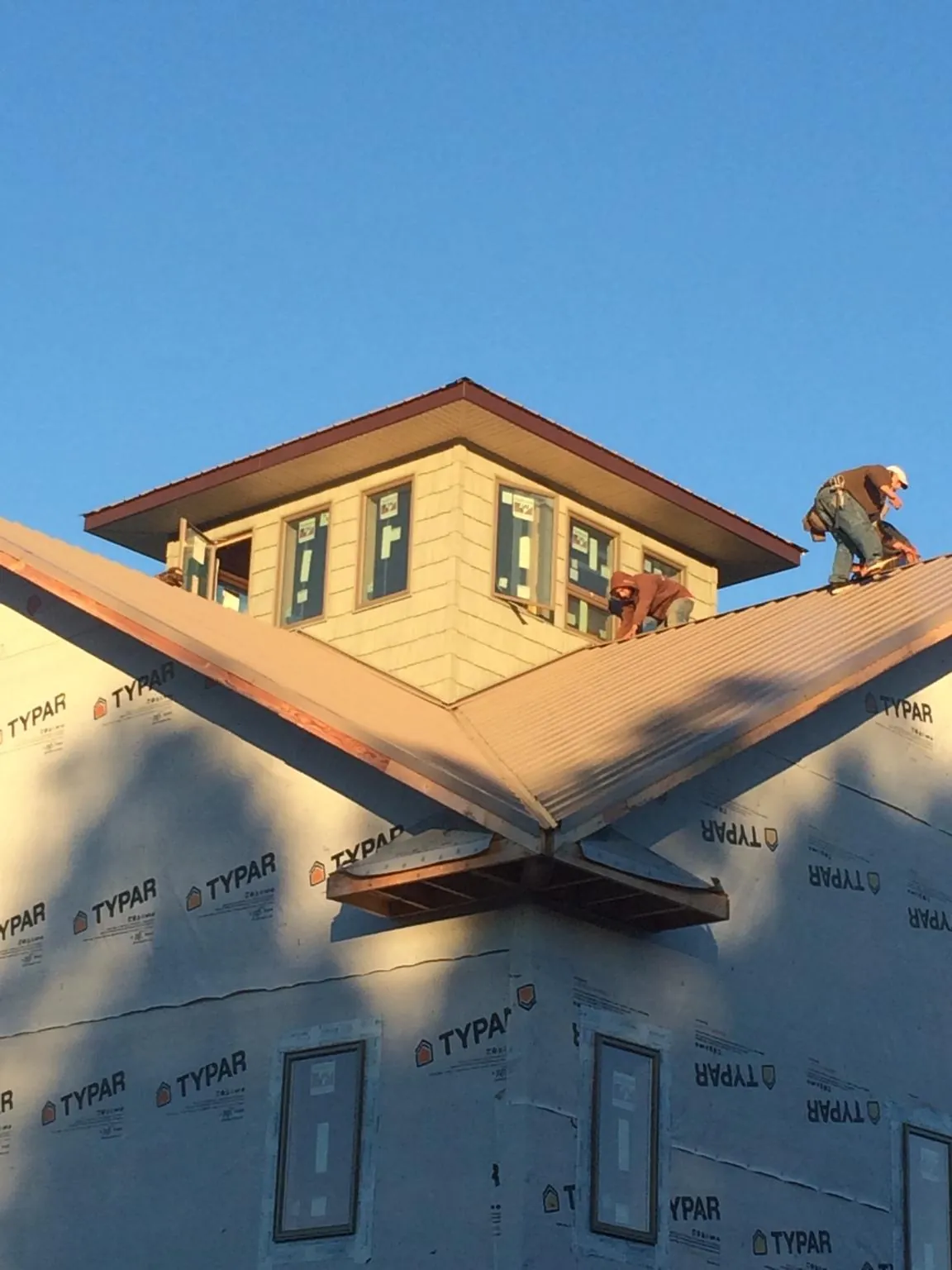 Roofers working around a rooftop cupola on a new metal roof at sunset — Roof Waterproofing in Ridgway by Roofing Brothers
